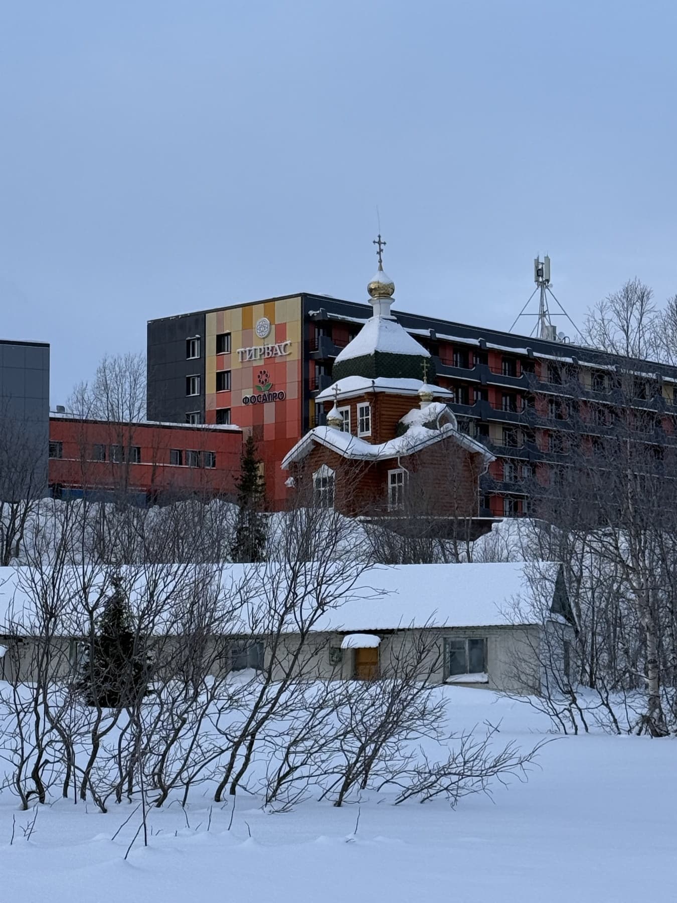 Церковь и красное здание в снегу в Кировске